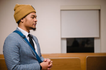 Image of Von Walker, board member, looking to the right in a blue suit and a tie, hands clasped, with a yellow beanie on.